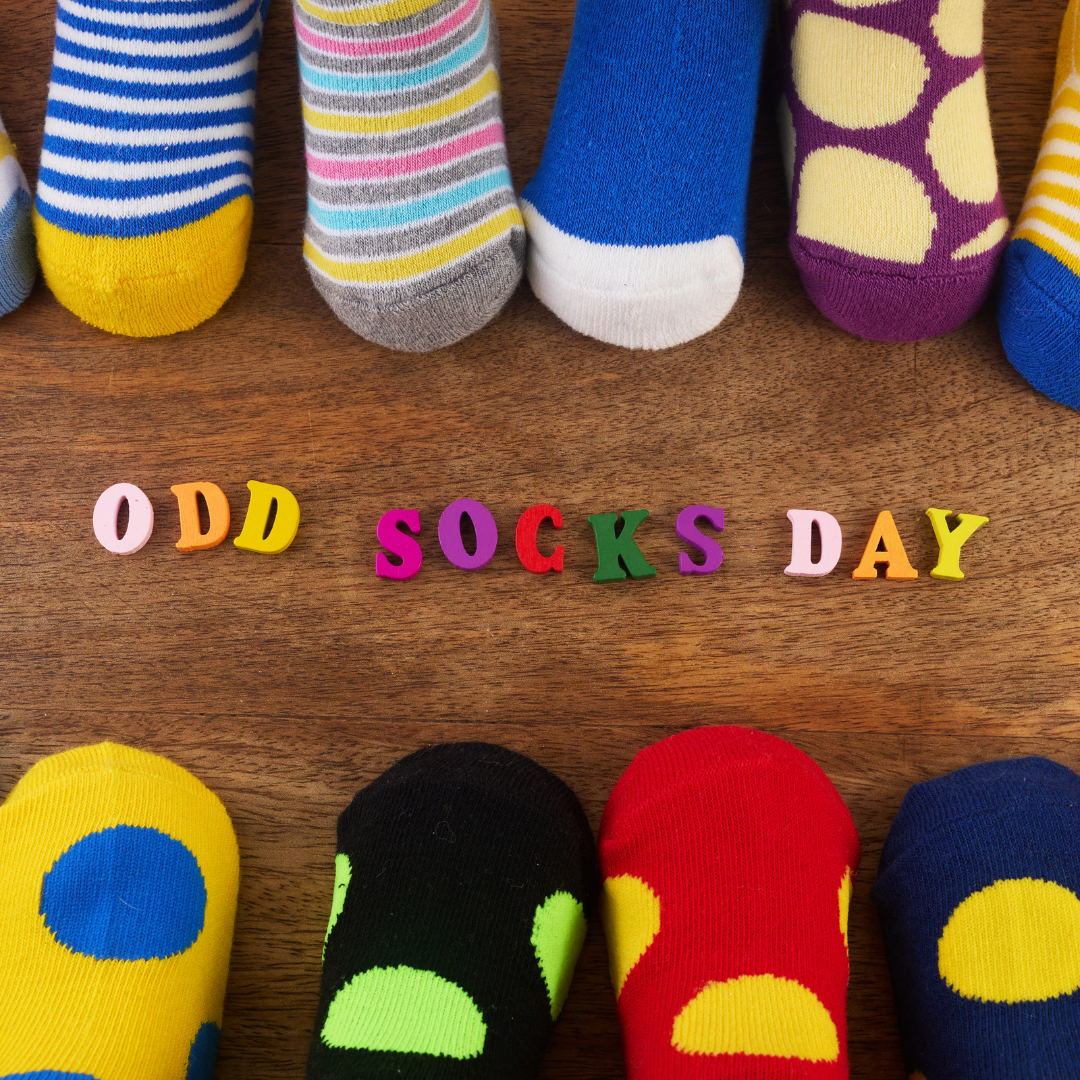 old socks on a range of feet in two lines facing each other, with odd socks day spelt out in colourful letters in the middle.